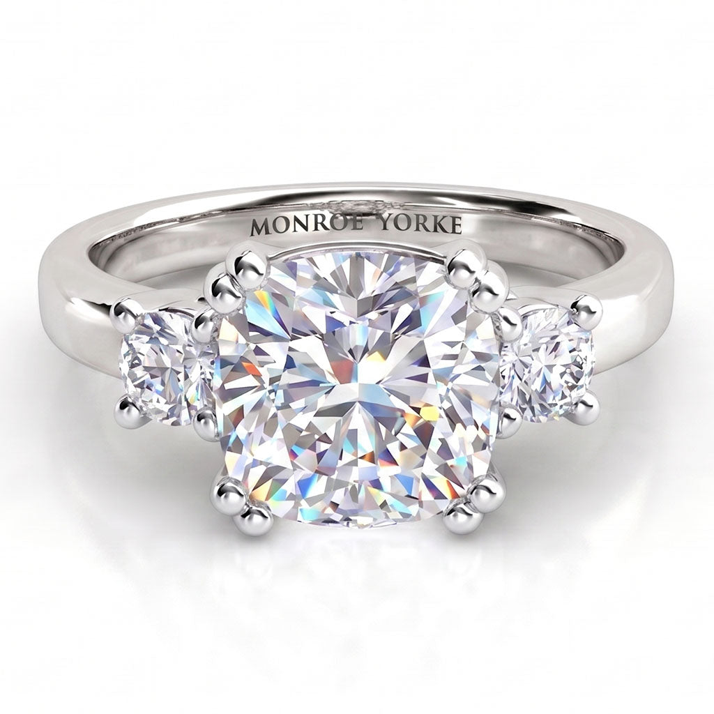 Meghan Markle's engagement ring. Three diamond ring with centre cushion cut diamond and round diamonds on either side. White Gold or platinum
