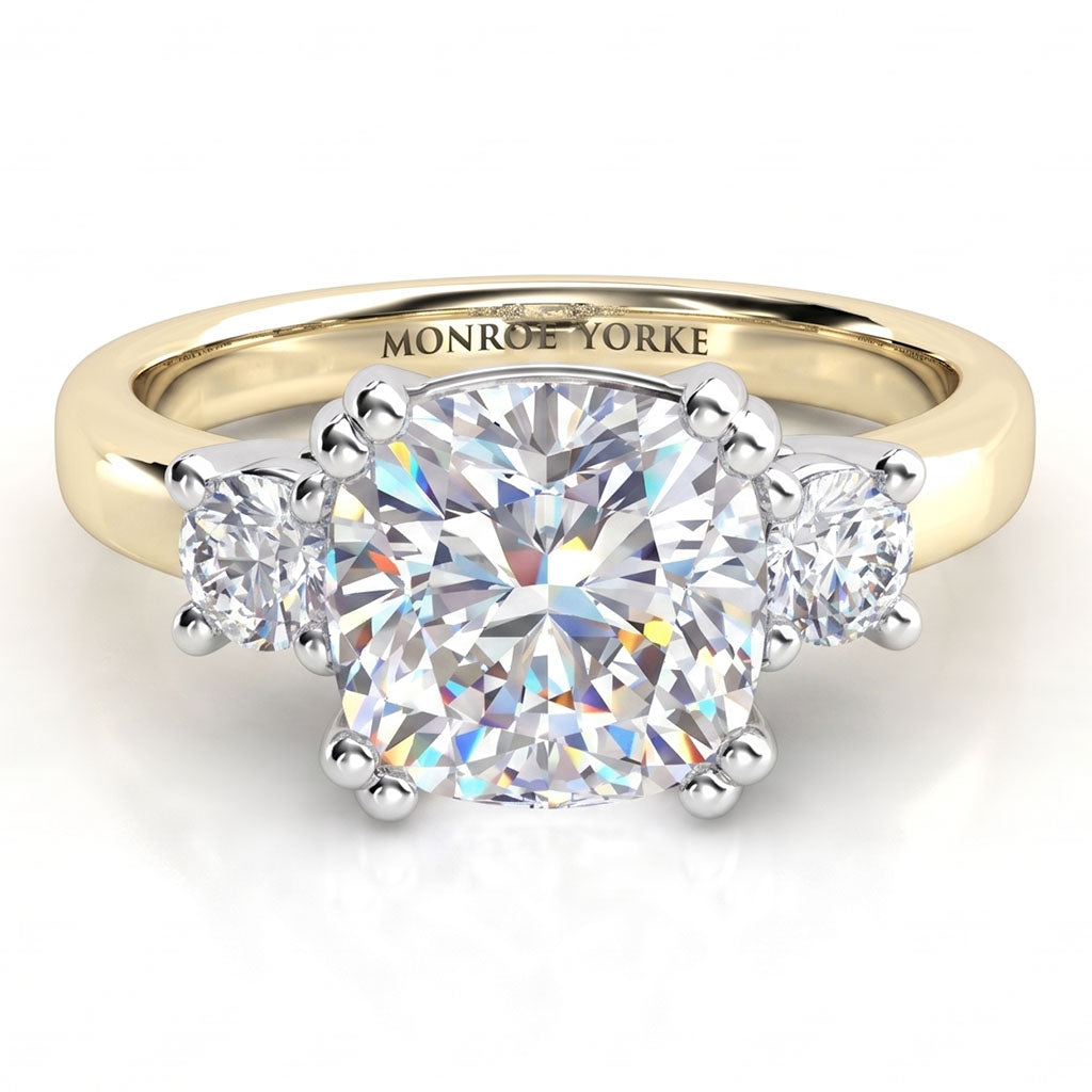 Meghan three diamond engagement ring worn by Meghan Markle. Centre cushion cut diamond with two round diamond on either side. Yellow Gold Band

