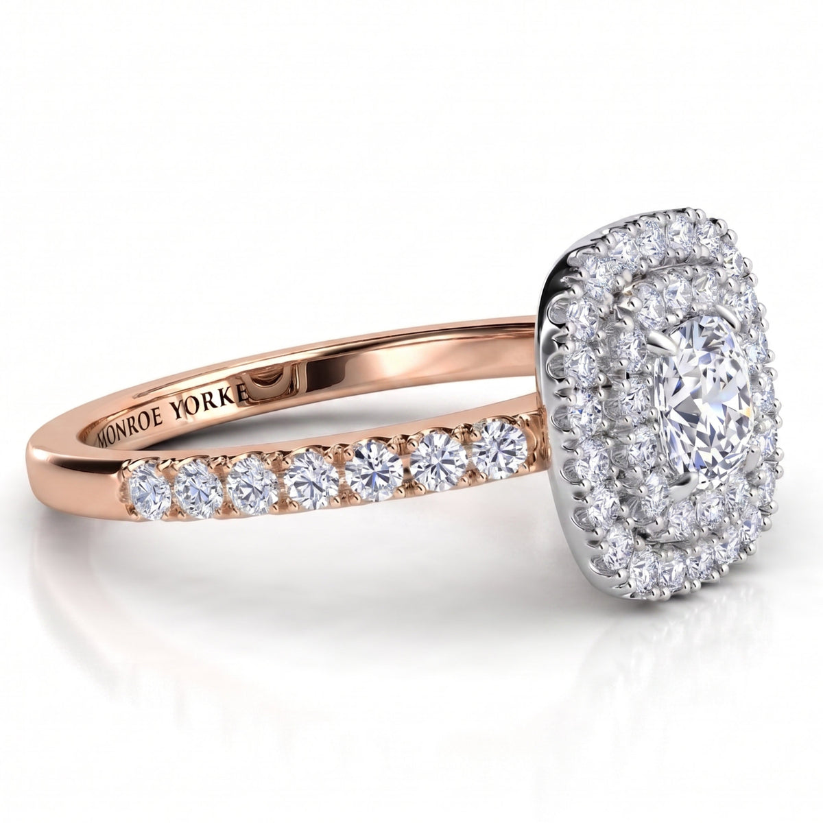 Norah cushion cut double halo engagement ring with a rose gold band, angled side view showing the depth of the two halos in the white metal setting head.