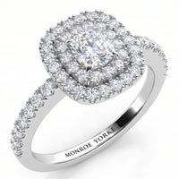 Norah double halo cushion cut engagement ring in white gold or platinum, angled view of the cushion cut centre diamond framed by two diamond halos, with round diamonds claw set down the band.