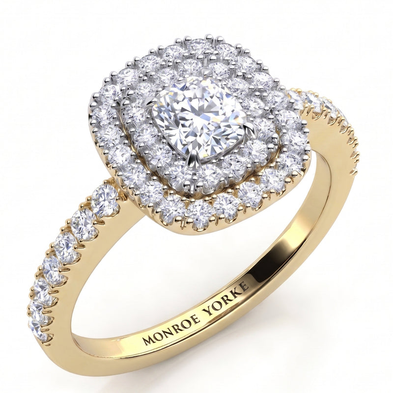 Norah double halo cushion cut engagement ring in yellow gold, angled view of the cushion cut centre diamond framed by two diamond halos in a white metal setting head, Monroe Yorke engraved inside the band.