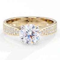 Sophia - A yellow gold solitaire engagement ring featuring a round brilliant-cut center stone and pavé-set side stones, with the brand name . 4 Claw centre setting