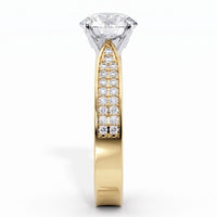 A yellow gold diamond ring with a large round-cut diamond solitaire and a pavé-set diamond band, shown on a clean white background.