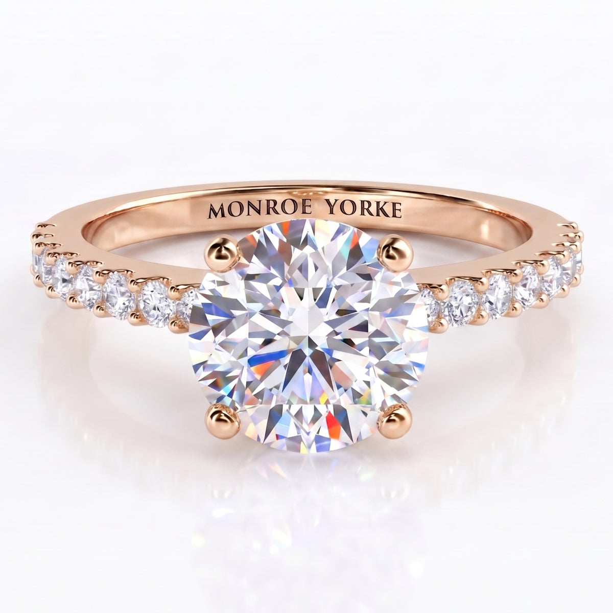 Spring - a rose gold engagement ring featuring a round brilliant-cut center diamond and a pavé-set diamonds on the band engraved with 'MONROE YORKE', 