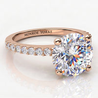 Rose gold diamond engagement ring with a large round-cut center stone and a pavé band.