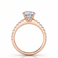 A rose gold engagement ring with a 4 claw centre setting and  a pavé set band of small diamonds