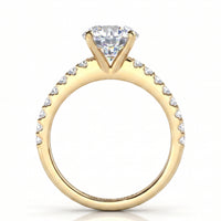 A yellow gold solitaire engagement ring featuring a round brilliant cut  center diamonds and a pavé band set with small round diamonds. 