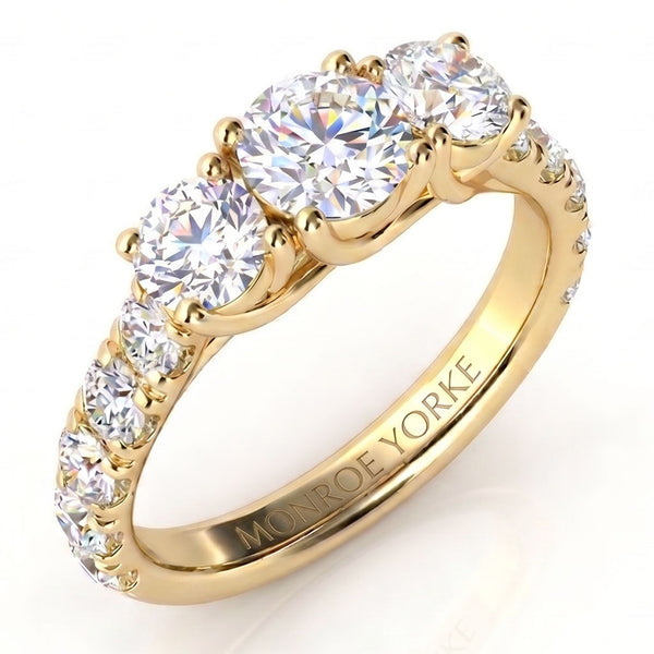A yellow gold three-stone ring with round brilliant-cut diamonds, featuring smaller diamonds along the band a