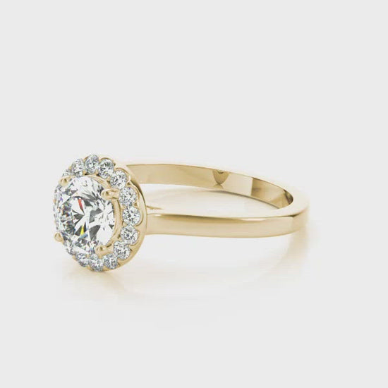 A diamond halo engagement ring created in rich yellow gold.  This diamond engagement ring design showcases a beautiful round brilliant cut diamond that is surrounded by a glistening halo of diamond accents. The stone and the halo are elevated above the band for all the world to see. This magnificent piece will be a perfect match for any of our wedding bands for a reminder of your eternal love.