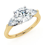 Adele diamond trilogy ring.  Three stone ring.  Centre round brilliant cut diamond and pear shaped diamonds.  Yellow gold. 