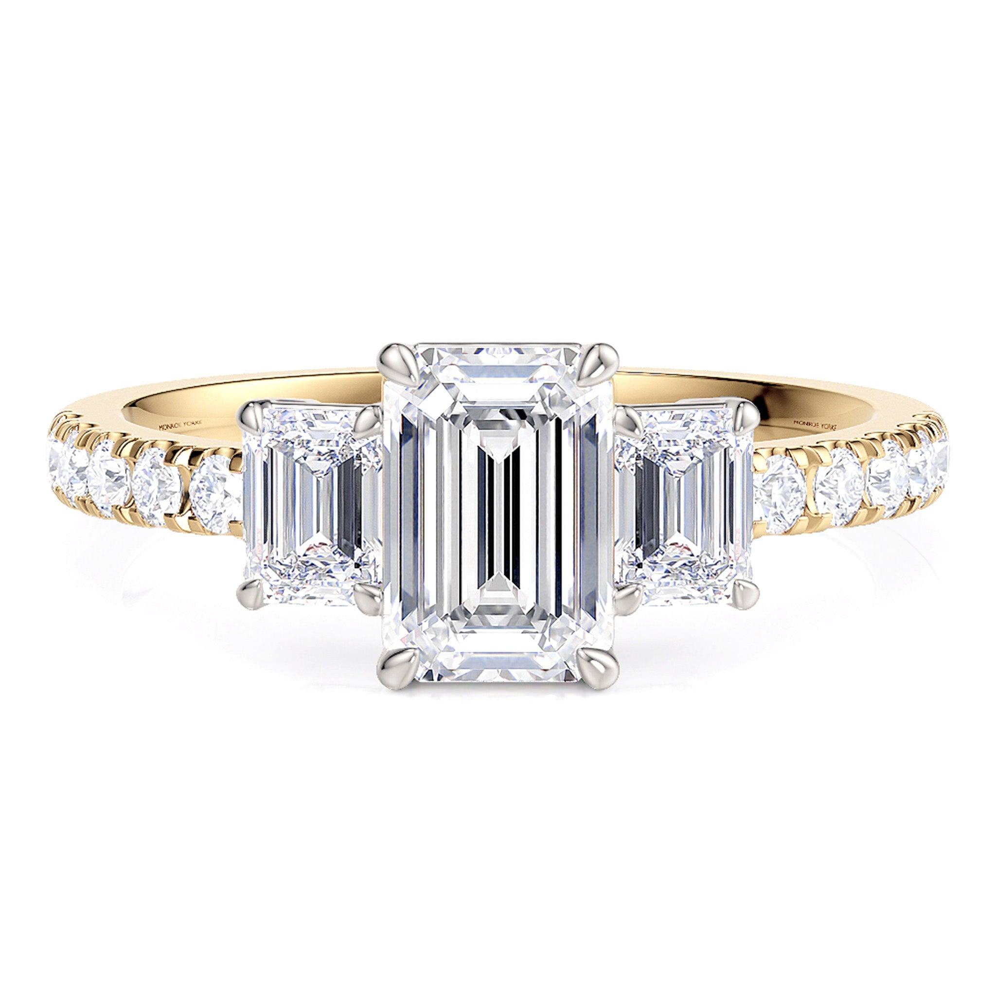 Aspen emerald cut diamond three stone ring with diamonds on the band. 18ct gold band and white gold centre setting