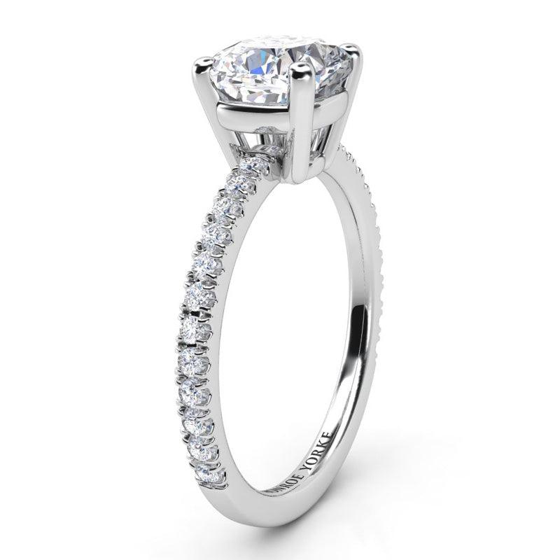 Blake - Side view showing centre cushion cut diamond in a basket setting.  Diamonds set 2/3 of the way around the platinum band.
