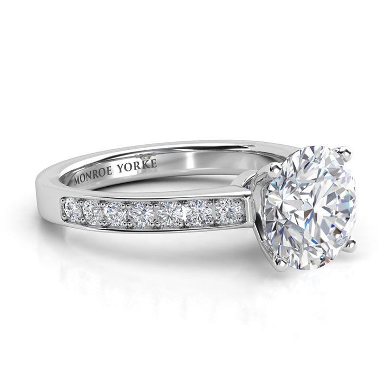 Danae - 18ct white gold. Round Brilliant Cut Diamond Engagement ring with side diamonds. 4 claw centre setting. Side view.