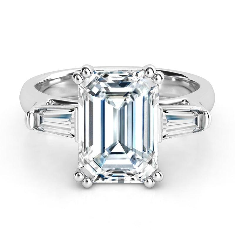Envy - Top view.  Emerald and tapered baguette diamond ring.  Emerald cut diamond held securely in double claws. 18ct white gold. Three stone ring.