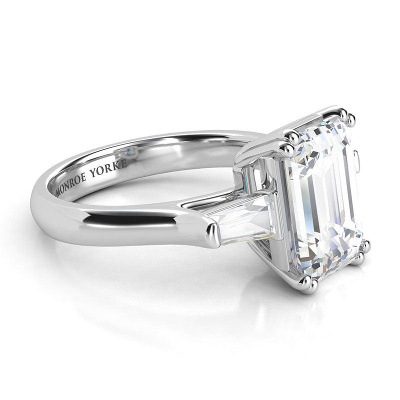 Envy Platinum - Emerald cut diamond and tapered cut baguette three stone ring.  Centre emerald cut diamond held in double claws. Side view — view 3