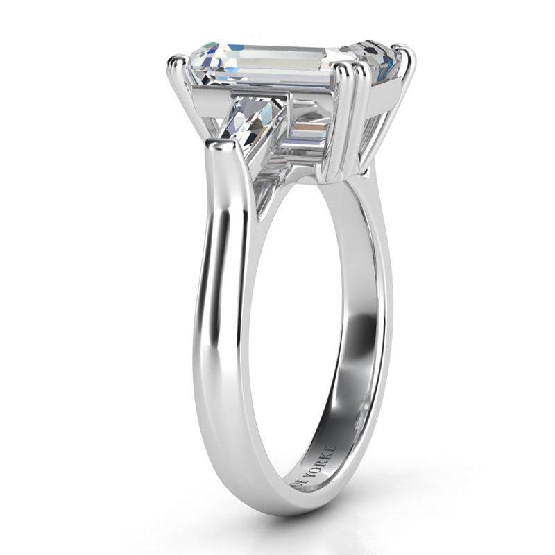 Envy Platinum - Emerald cut diamond and tapered cut baguette three stone ring. Side view showing centre setting. 