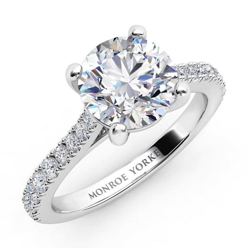 Enya in platinum.  Round diamond engagement ring with diamonds down the band. 