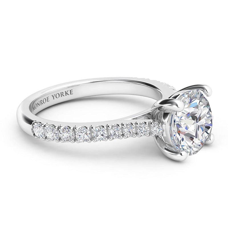Enya - Side view. GIA certified round diamond engagement ring in a 4 claw setting with diamonds on the sweep up band. 18ct white gold