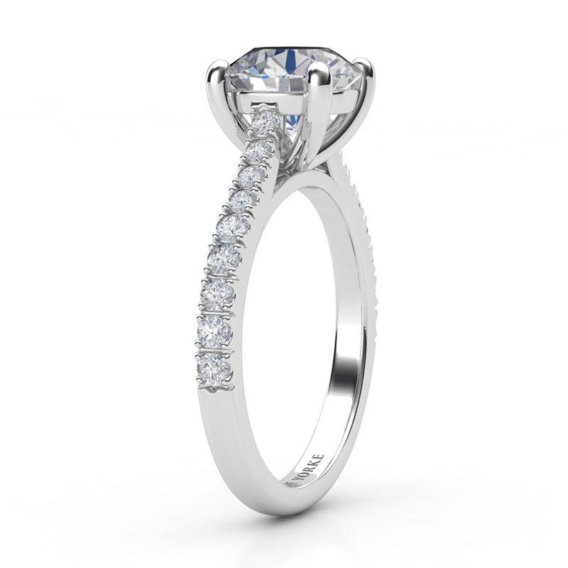 Enya - Side view. GIA certified round diamond engagement ring in a 4 claw setting with diamonds on the sweep up band. 18ct white gold
