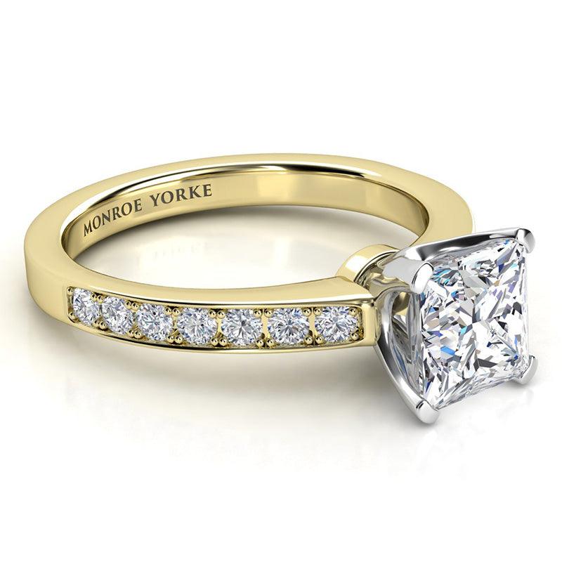 Fifth Avenue yellow gold side view: centre princess cut diamond set in a white gold setting.  Diamonds set on the sweep up band. 