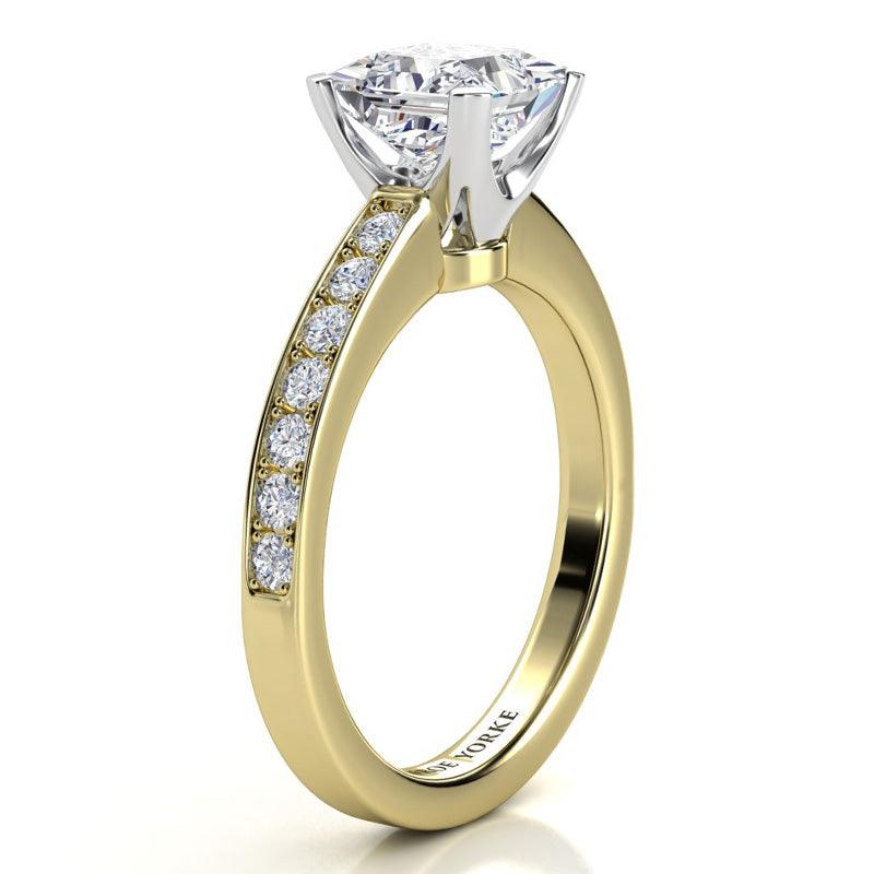 Fifth Avenue yellow gold side view: centre princess cut diamond set in a white gold setting.  Diamonds set on the sweep up band. 