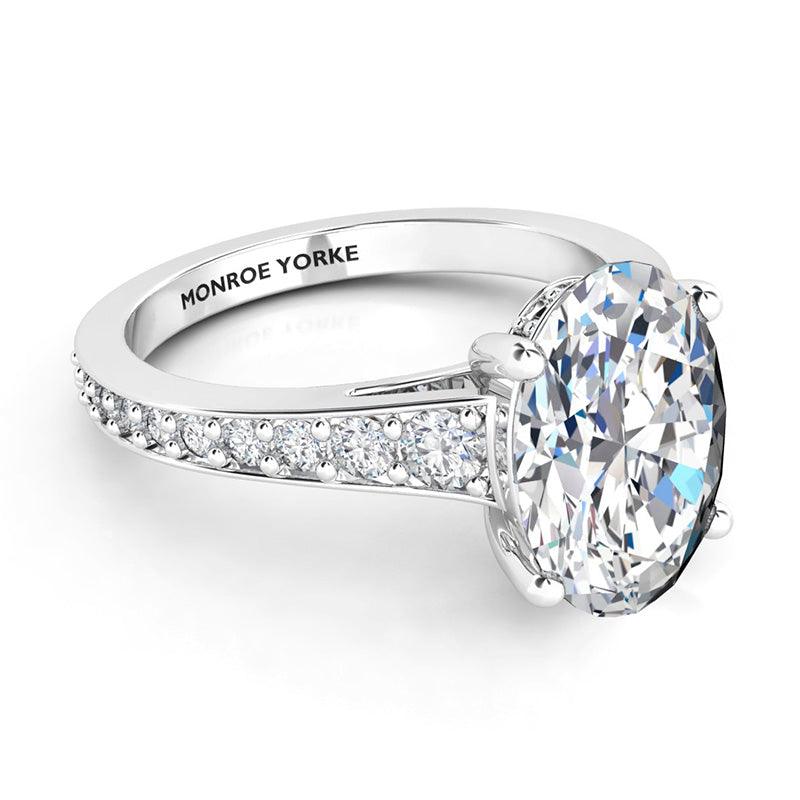 Finley engagement ring in platinum.  Graduated band with diamonds. Centre oval cut diamond. Hidden halo around the side of the diamond around its girdle