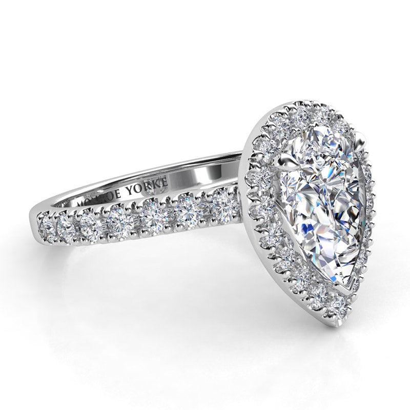 Pear cut diamond halo engagement ring.  Side view showing:  round brilliant cut diamonds on the sweep up band 