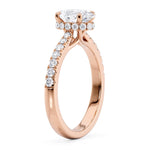 Side view of the Paige oval diamond ring.  Arms extend out of the claws, cross over under the centre setting and becomes the claws that hold the main oval diamond. The band that tapers into the centre setting is also visible here. 