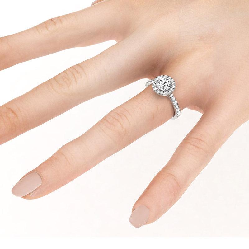 Serene Platinum - Round halo diamond ring with diamond on the band shown on a hand.  